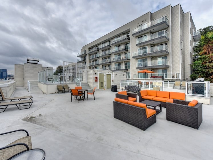 Rooftop Lounge Area with Orange Sofa, Lounge Chairs and Apartment Exterior